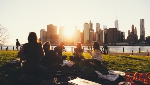 A group of friends on blanket in a park talking.