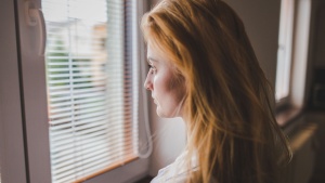 A young woman staring out a window.