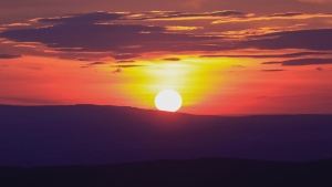 A sun setting over a hill.