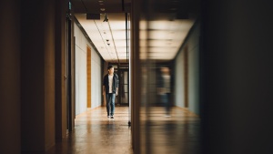A young guy walking in the hallway of a building.