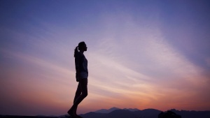 A woman with the a sunset sky in the background.