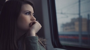 A woman looking out of a window on a commuter train.