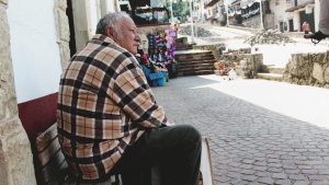 A old man sitting on a bench in an old village.