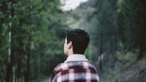 A young man walking looking down a path.