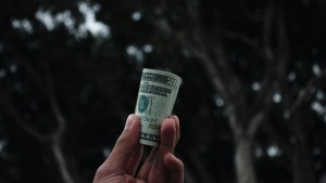 A man holding a folded $20 bill. 