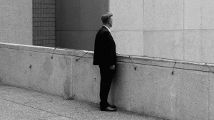 A man standing on walk way between buildings.