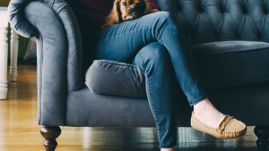 A woman sitting on a couch holding a small dog in her lap.