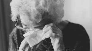 An elderly lady wiping her eyes.