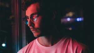 A young man staring at neon sign on a window.