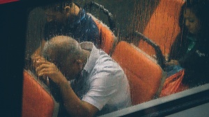 People riding a commuter train while raining. 