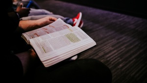 A Bible on the lap of young man.