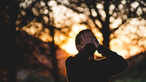 A man with his hands on his face looking up.