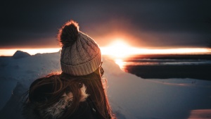 A woman who is warmly dressed watching the sunset.