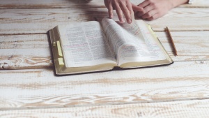 A person studying a Bible on a table.