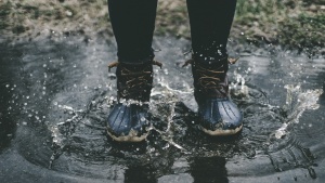 A person wearing boots standing in a puddle.