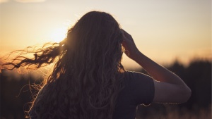A young woman looking at the setting sun.