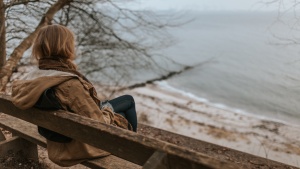 A woman sitting on a bench overlooking water.