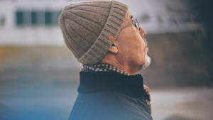 An older man wearing a beanie to keep head warm.