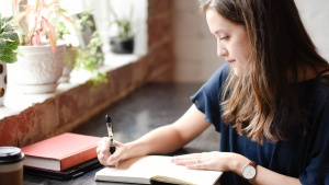 A woman writing in a journal notebook.