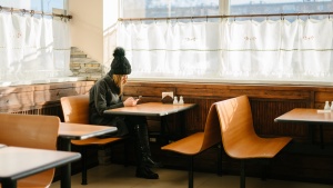 A young woman sitting a small table inside a restaurant. 