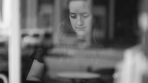 A young woman typing on a laptop at a counter of a cafe.