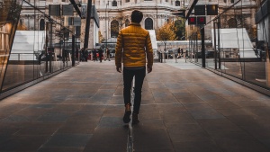 A man walking down a road in between to buildings.