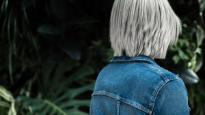The back of young woman wearing a blue jean jacket.