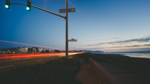 A green light on busy street next to the ocean.