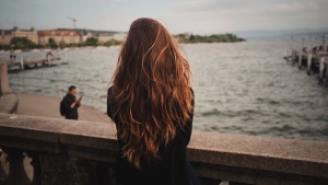 A woman standing on a bridge and looking out over the water.