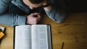 A man reading a Bible on a table.