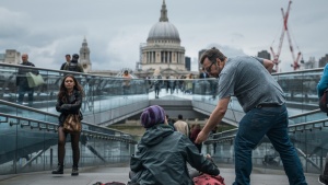 A man giving a donation to a homeless person.