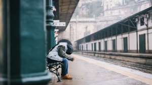 A man sitting a train terminal with his head down.