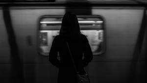 A woman standing by a subway train as it passes by.