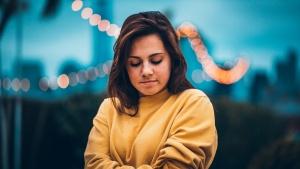 A young woman with her arms crossed and looking down.