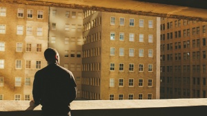A person looking out over a wall at buildings in a city.