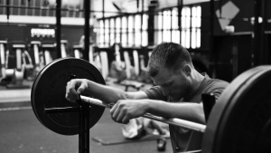 A man resting his arms on a weight lifting bar.
