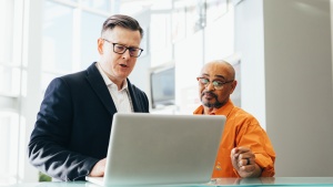 Two men discussing a topic around a laptop.