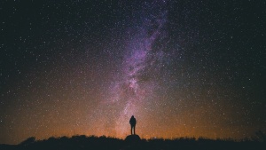 A person standing at night with stars in the background.