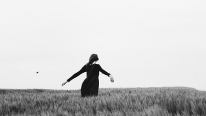 A woman with her arms open walking through a field.