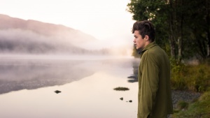 A young man looking out over a lake.