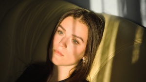 A woman sitting on a couch while her head is resting on cushion.