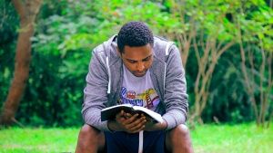 A man sitting on a bench reading a Bible.