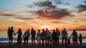 A big family gathering at the beach at sundown.