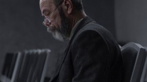 A man sitting in hall with chairs looking at notes.