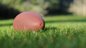 An American football on a grass field.