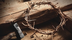 A wooden cross/stake with a crown of thorns, hammer and nails.