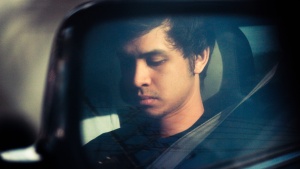 Reflection of a man in a car side mirror.