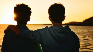 Photo of two boys looking at the sunrise together.