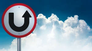 A u-turn type sign with the sky and clouds in the background.