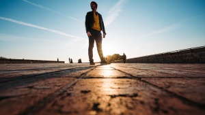 A man walking on a cobblestone sidewalk.